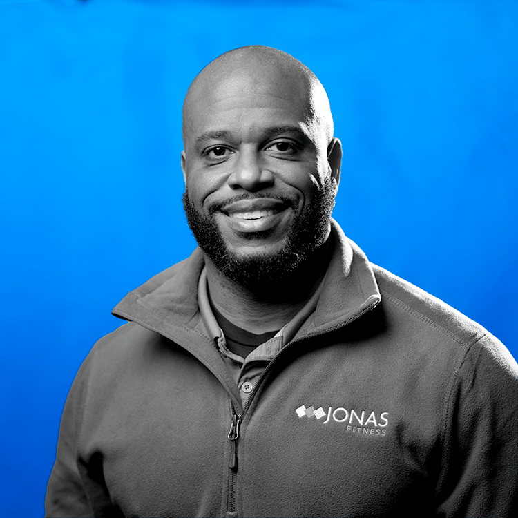 Headshot photo of Jonas Fitness' Client Support Services Manager, Jason Poole, standing in front of a blue background.