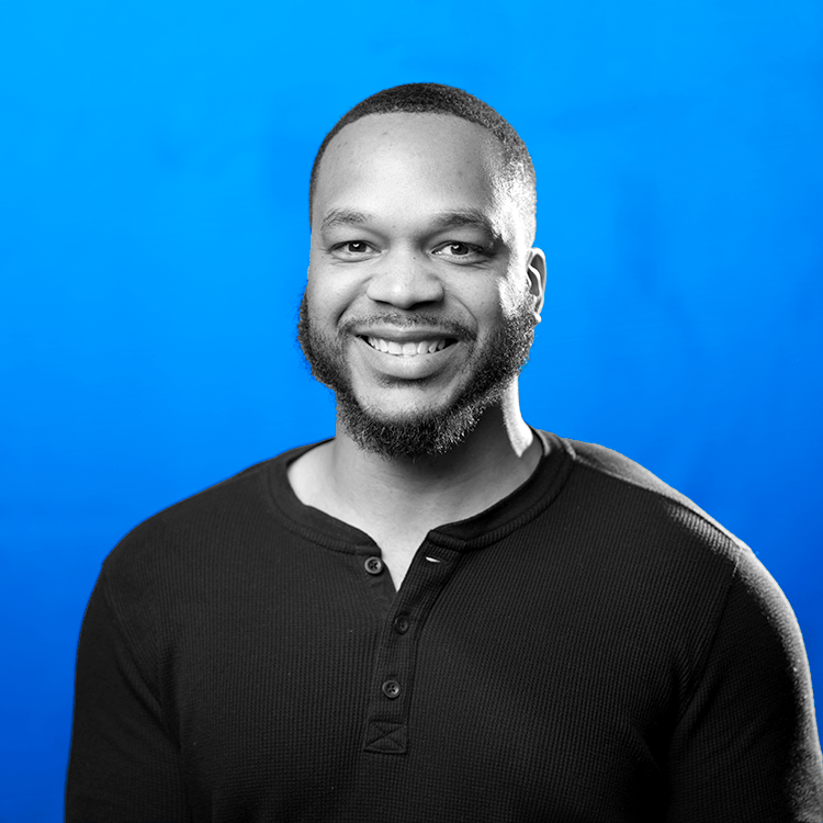 Headshot photo of Jonas Fitness' Client Success Manager, Lonnie Hewitt, standing in front of a blue background.