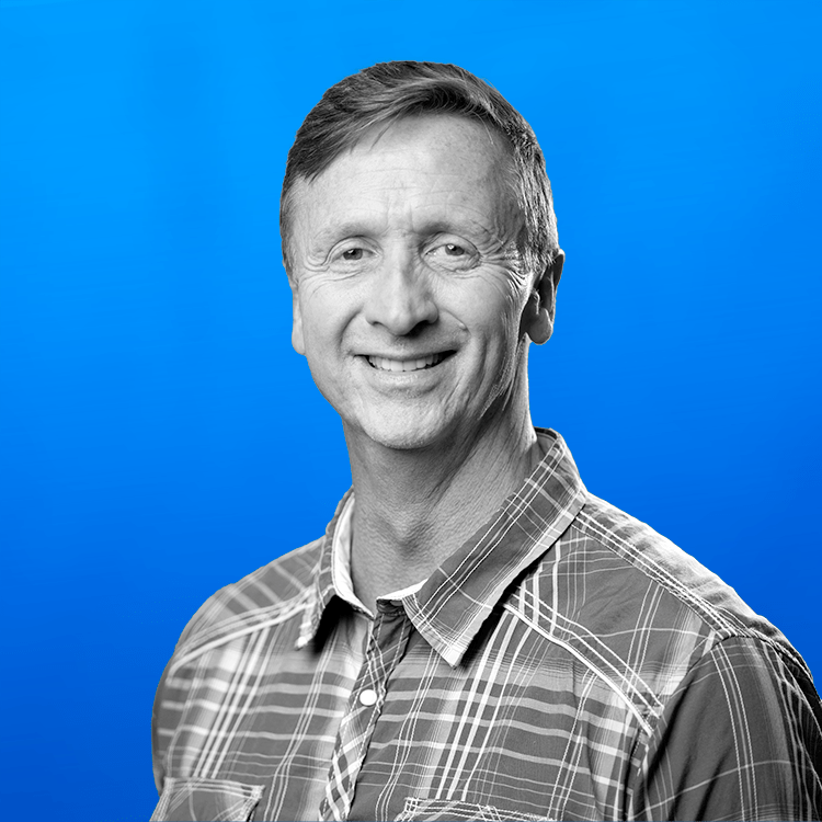 Headshot photo of Jonas Fitness VP of Sales, Sean Kirby, standing in front of a blue background.